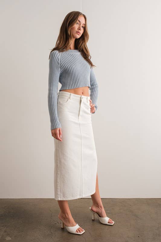 Woman wearing a light blue mock neck long sleeve rib knit cropped sweater.