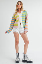 Woman wearing a colorful striped cardigan in pink, blue, green, orange, and lilac with a button-front closure.