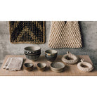 Set of ceramic bowls and woven items on a wooden surface with a textured wall background.