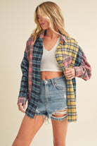Woman wearing an oversized plaid colorblock flannel shirt in pink, yellow, and navy tones with raw hems.