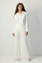 White pleated chiffon flared trousers with high waist and flowy wide legs.
