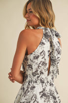 Woman wearing a halter neck tiered maxi dress with black floral print and ruffle layers