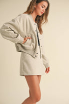 Model wearing a wool-blend jacket and mini skirt set in a neutral tone, styled with a striped tee and relaxed fit, showcasing casual elegance.