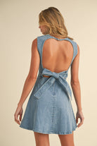 Sleeveless A-line denim mini dress with structured seams and light blue wash