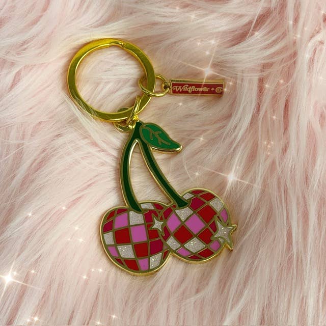 Disco Cherries Enamel Keychain featuring a pair of cherries with a sparkling, disco ball-inspired design on a pink background.