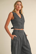 Woman wearing a sleeveless pinstriped vest and matching high-waisted wide-leg trousers.