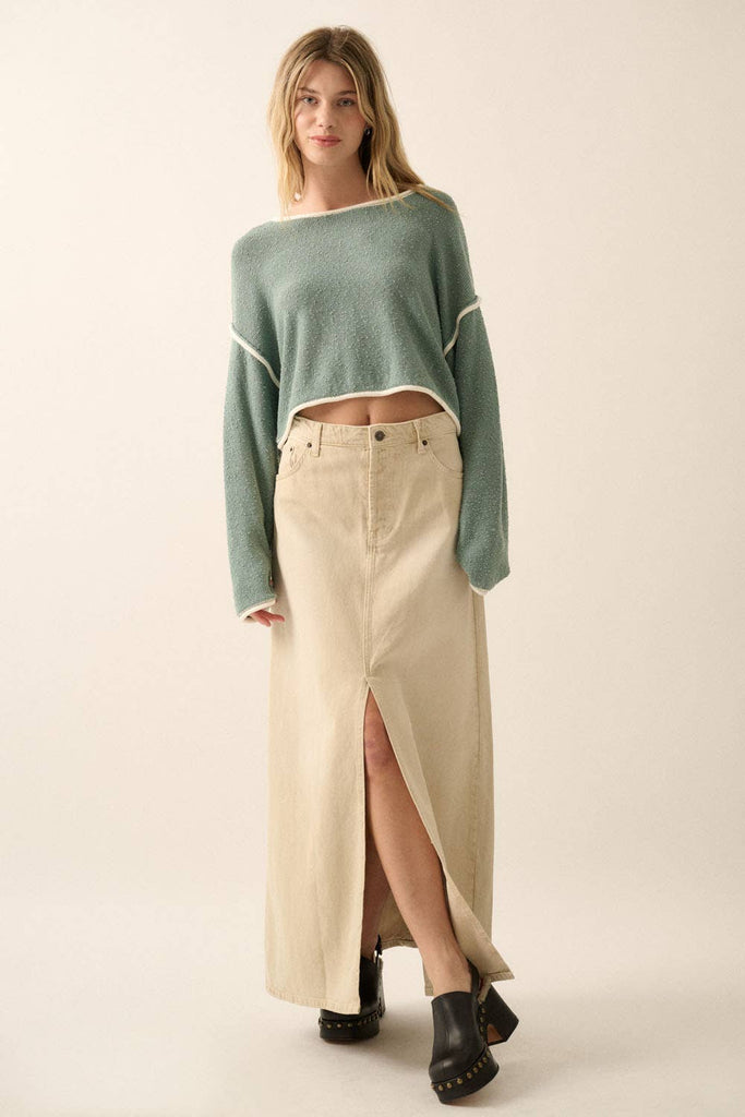 Woman wearing a sage green off-shoulder cropped sweater with white trim details and long sleeves.