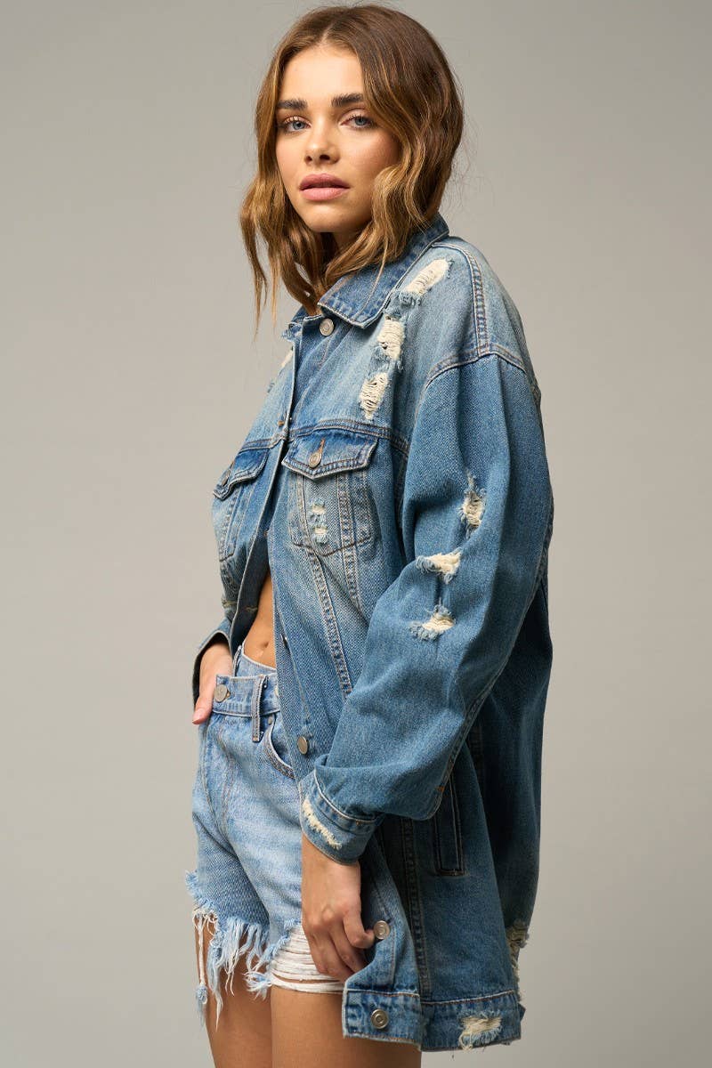 Close-up of asymmetrical distressed denim shorts with frayed hem and high-waisted fit.