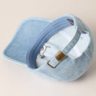 Light blue baseball cap with embroidered design on a beige background