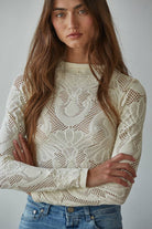 Model wearing the Celestine Lace Top in cream and black lace with long sleeves and floral mesh pattern