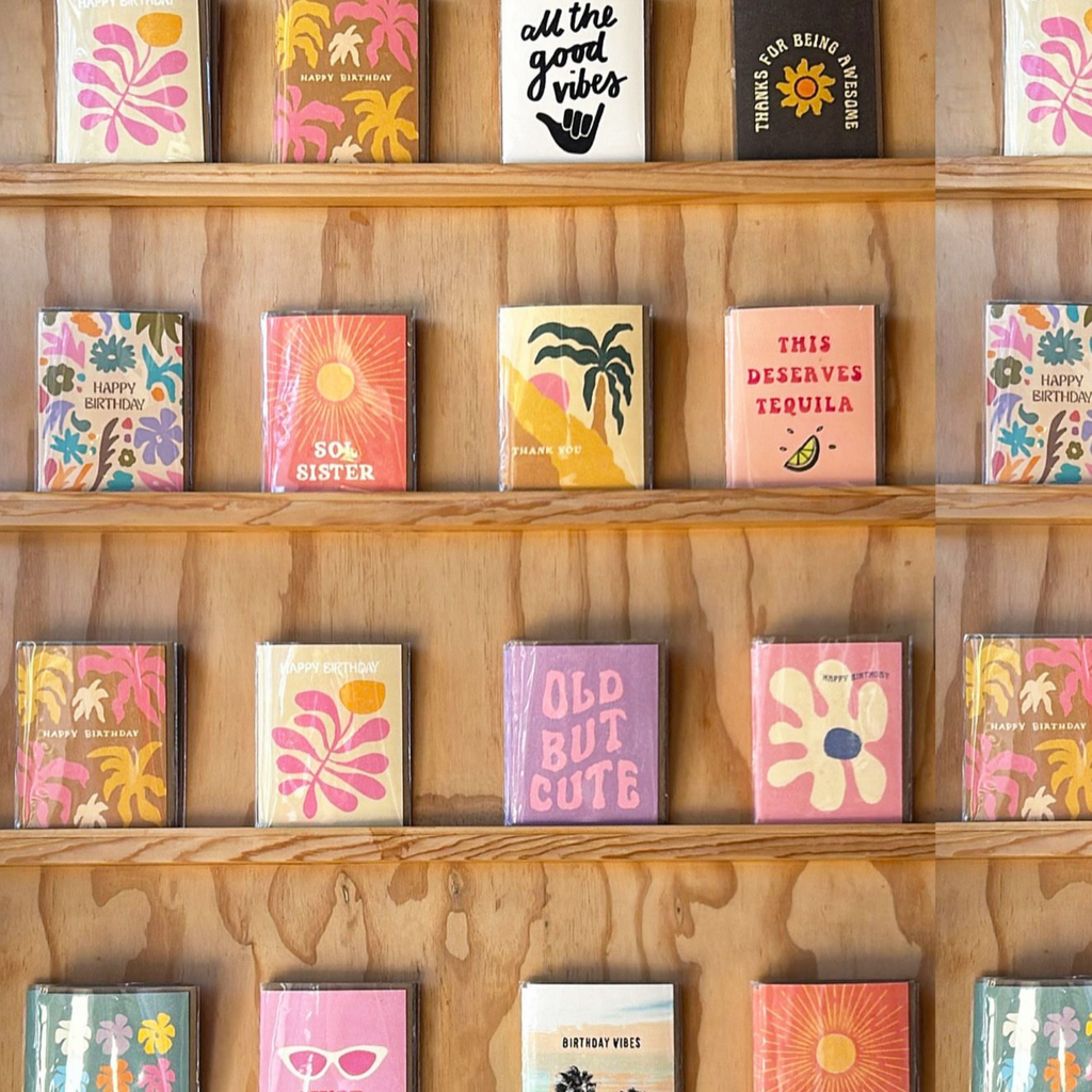 A peach-colored greeting card with red text reading "This Deserves Tequila" and a lime slice illustration, placed on a brown envelope.