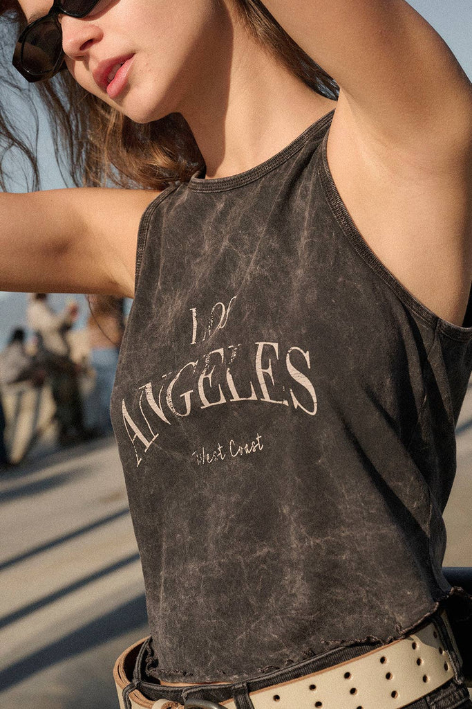 Washed black sleeveless tank top with "Los Angeles West Coast" text, styled with distressed black denim shorts.