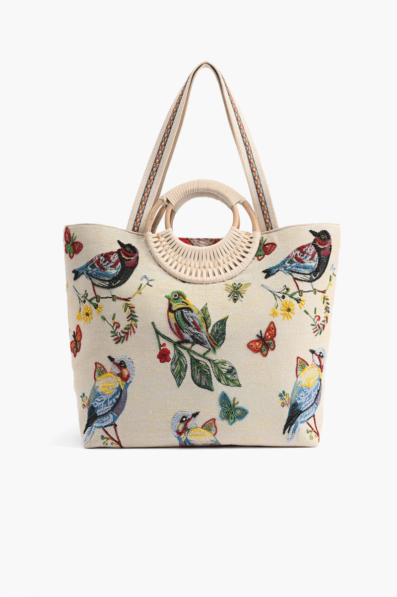 Beige embroidered tote bag with colorful birds, butterflies, and leaves, featuring round woven handles and shoulder strap.