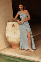 Model wearing a light blue two-piece set featuring a knotted tie-front crop top and button-front high-slit maxi skirt.
