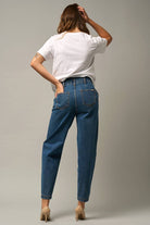  Model wearing high-waist balloon jeans with a relaxed silhouette and slightly tapered legs, paired with a casual graphic t-shirt and neutral heels.