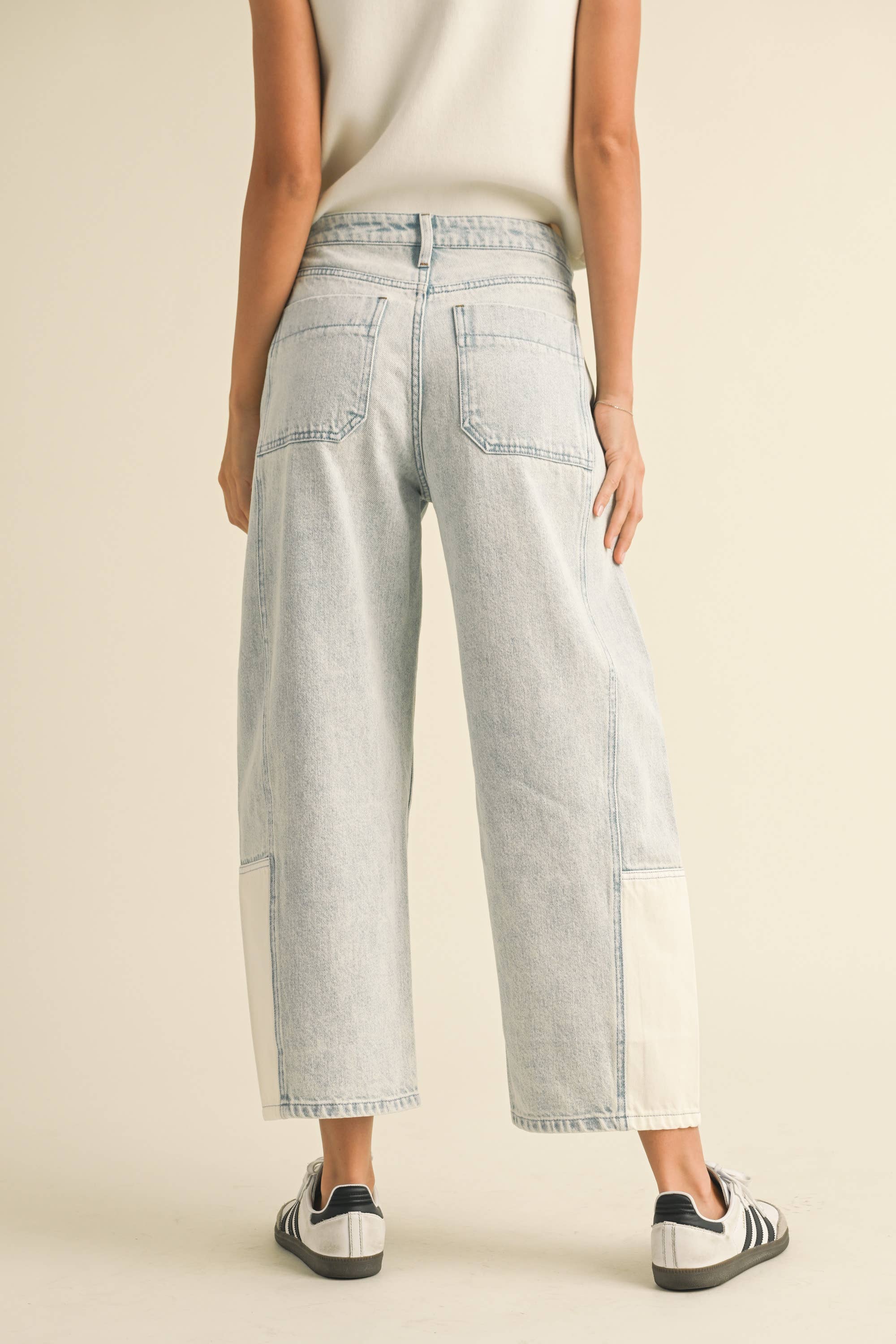 Model wearing light-wash wide-leg jeans with white contrast panels on the lower leg, styled with sneakers.