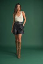 Model wearing a sleeveless ribbed knit top with deep V-neck and cross-back strap detail.