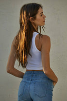 Woman wearing a fitted waffle-texture cropped tank top in green and white, styled with casual denim and neutral pants.