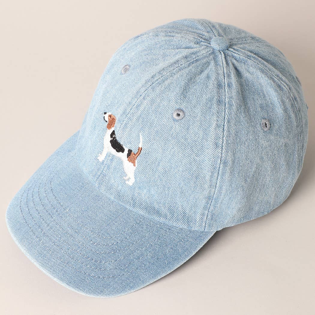 Light blue denim cap with embroidered dog design on a beige background