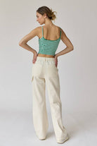Woman wearing a green and white stripe rib knit tank top with thin straps and high-waisted beige shorts.