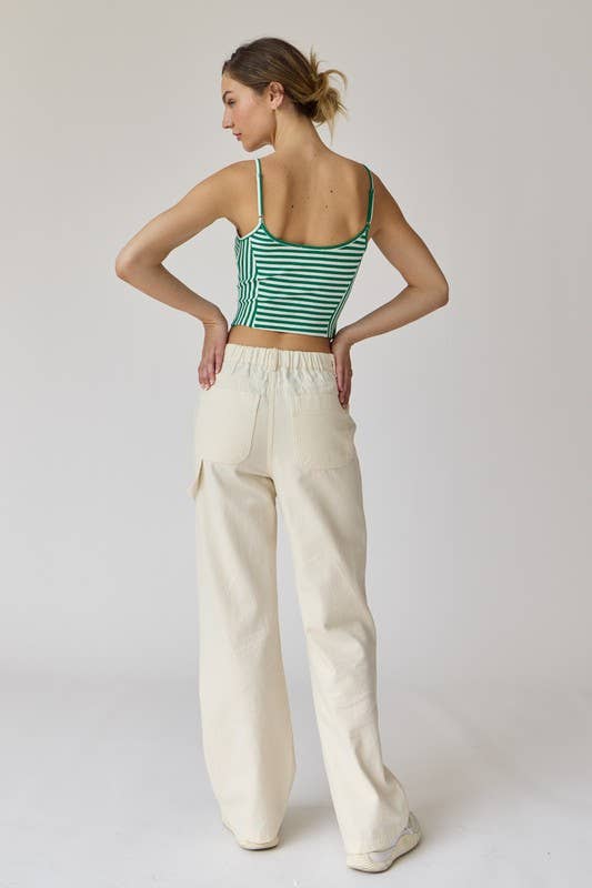 Woman wearing a green and white stripe rib knit tank top with thin straps and high-waisted beige shorts.