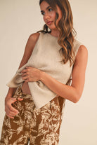 Woman wearing a beige ribbed knit tank top with side ties, paired with floral wide-leg pants