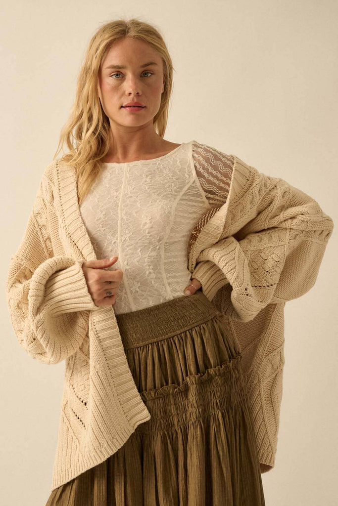Woman wearing a beige cardigan over a white top and brown skirt on a plain background