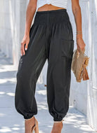 Woman wearing Serenity High-Waist Comfort Pants in beige and olive colors, paired with a white crop top and heels, carrying a decorative clutch.