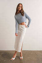 Woman wearing a light blue mock neck long sleeve rib knit cropped sweater.
