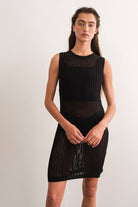 Woman wearing a sleeveless black crochet mini dress.