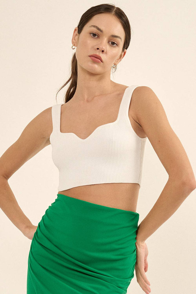 Woman wearing a white ribbed knit crop top with a sweetheart neckline and wide straps.