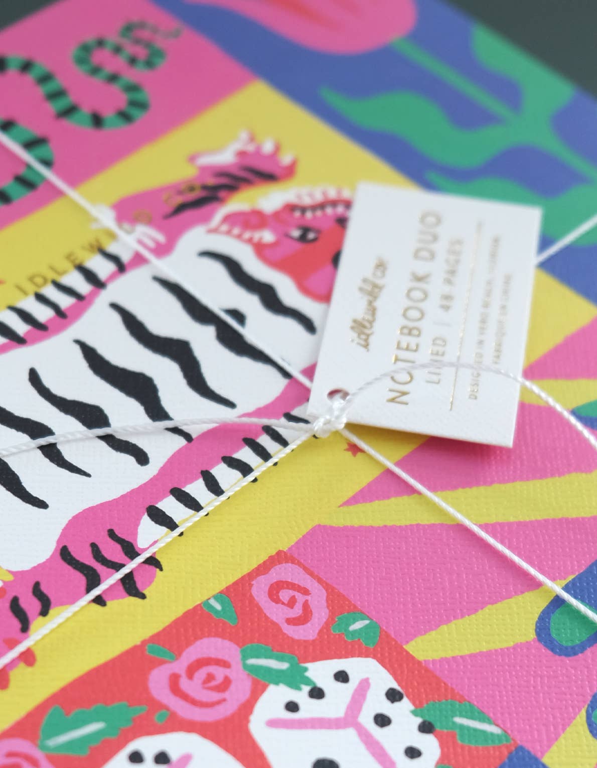 Colorful notebook with zebra pattern bookmark and brand tag on a multicolored background