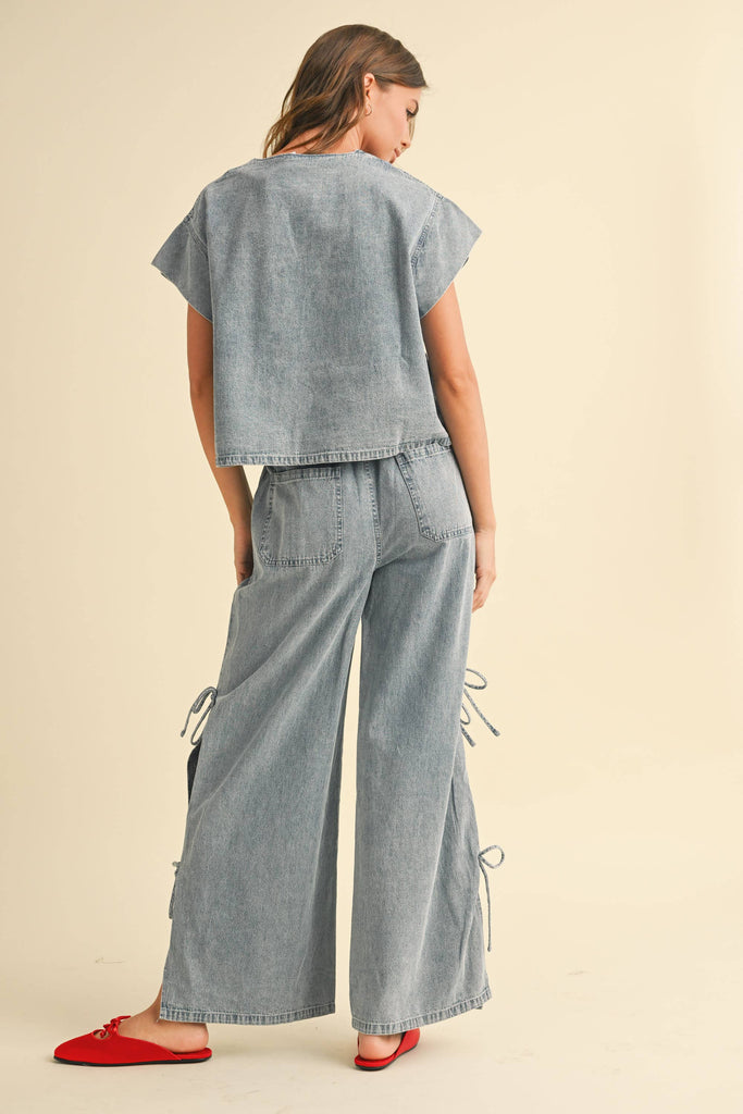Woman wearing a light-wash denim two-piece set with tie-front top and wide-leg pants featuring side tie accents.