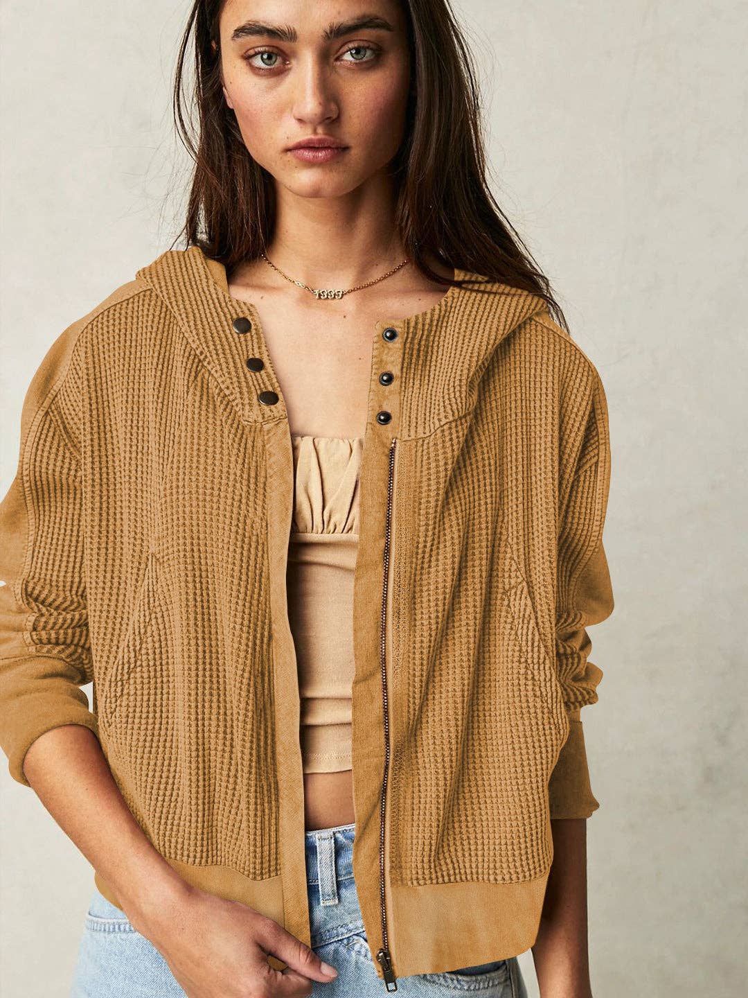 Woman wearing a Sahara Sky Hooded Jacket with a zip-up front, textured waffle knit, and button detailing in blue and brown tones.