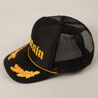 Black cap with gold embroidery on a beige background