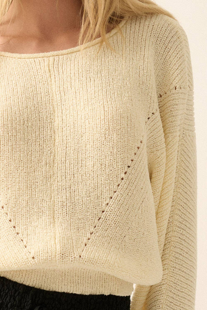 Woman wearing a cream lightweight knit sweater with wide sleeves and a cropped fit.