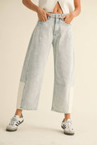 Model wearing light-wash wide-leg jeans with white contrast panels on the lower leg, styled with sneakers.