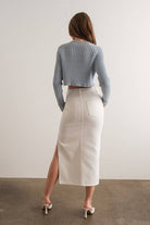 Woman wearing a light blue mock neck long sleeve rib knit cropped sweater.