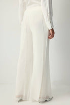 White pleated chiffon flared trousers with high waist and flowy wide legs.