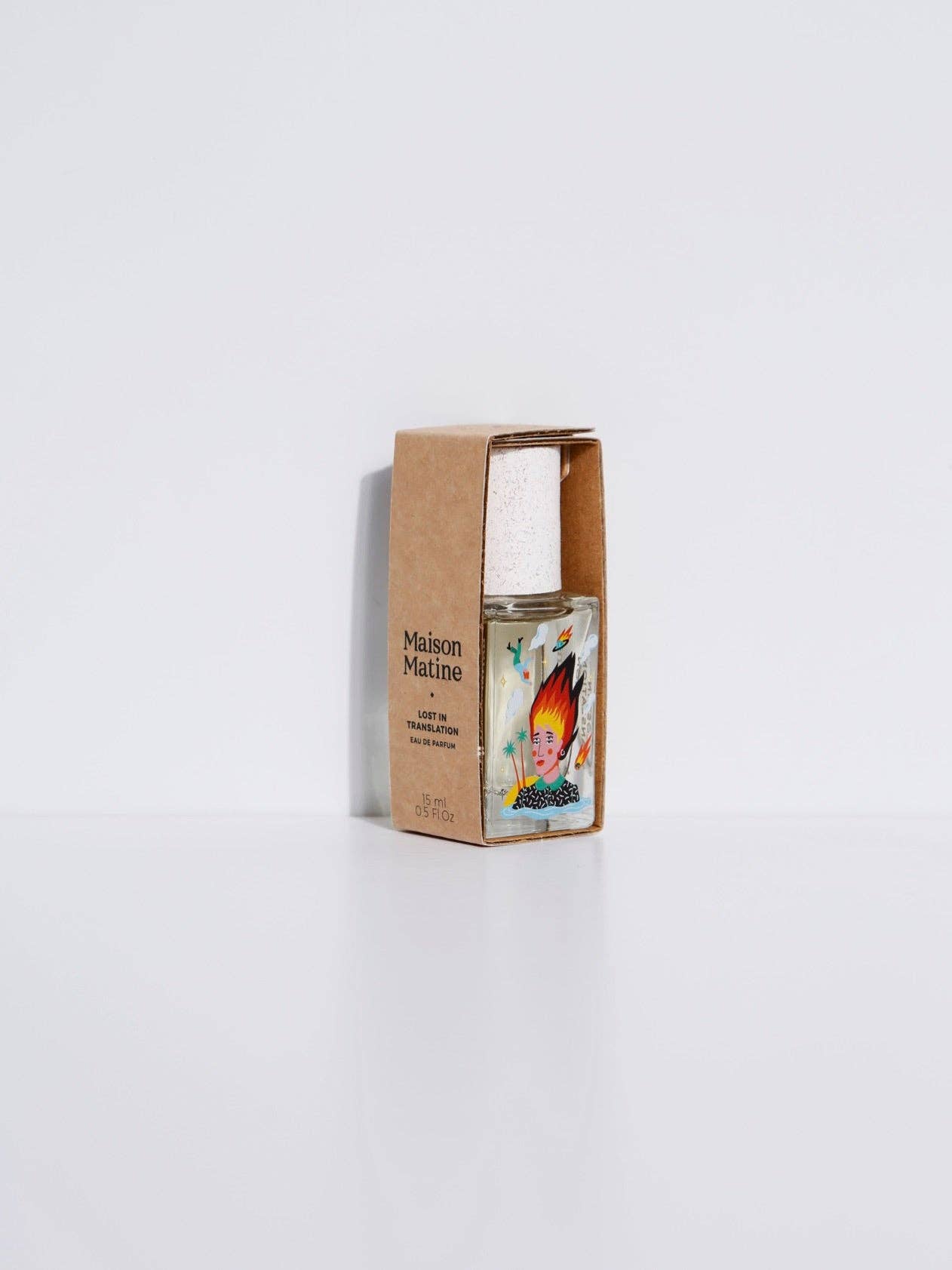 Maison Matine Lost in Translation perfume bottle with bold illustrated design, placed on vibrant yellow textured surface.