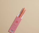 Pink pencil case with orange pencils on a beige background