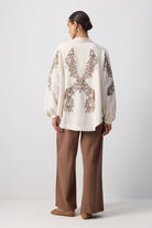 Back view of a woman wearing a cream embroidered kimono with sequin detailing and wide sleeves.