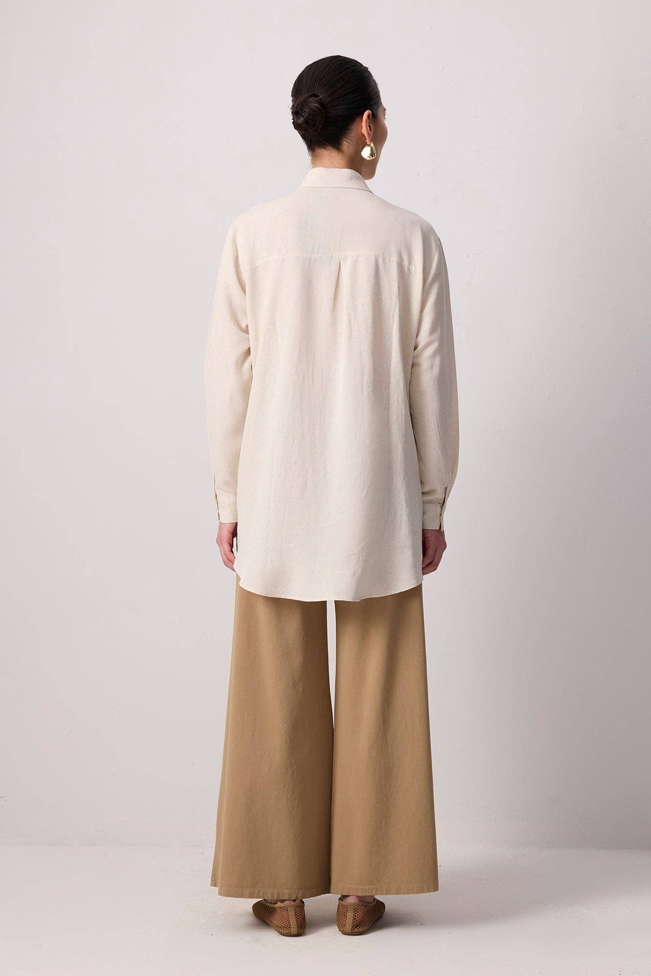 Model wearing a beige button-up shirt with floral embroidery and beaded detailing
