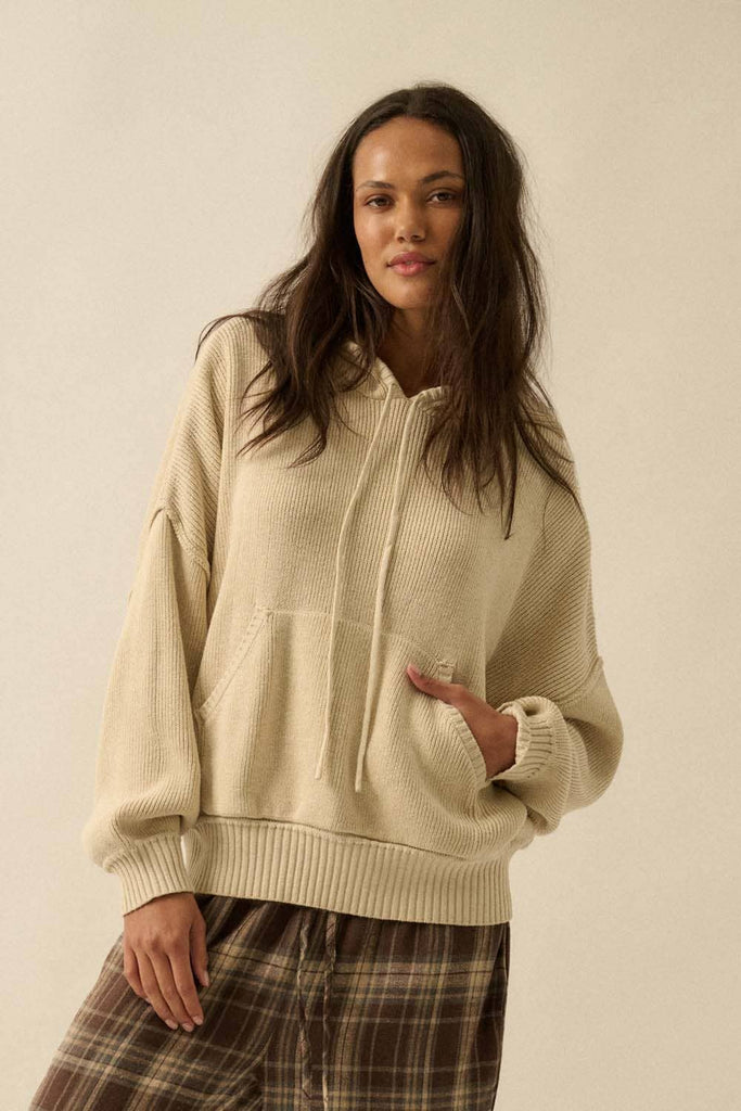 Woman wearing a cream-colored hoodie against a beige background