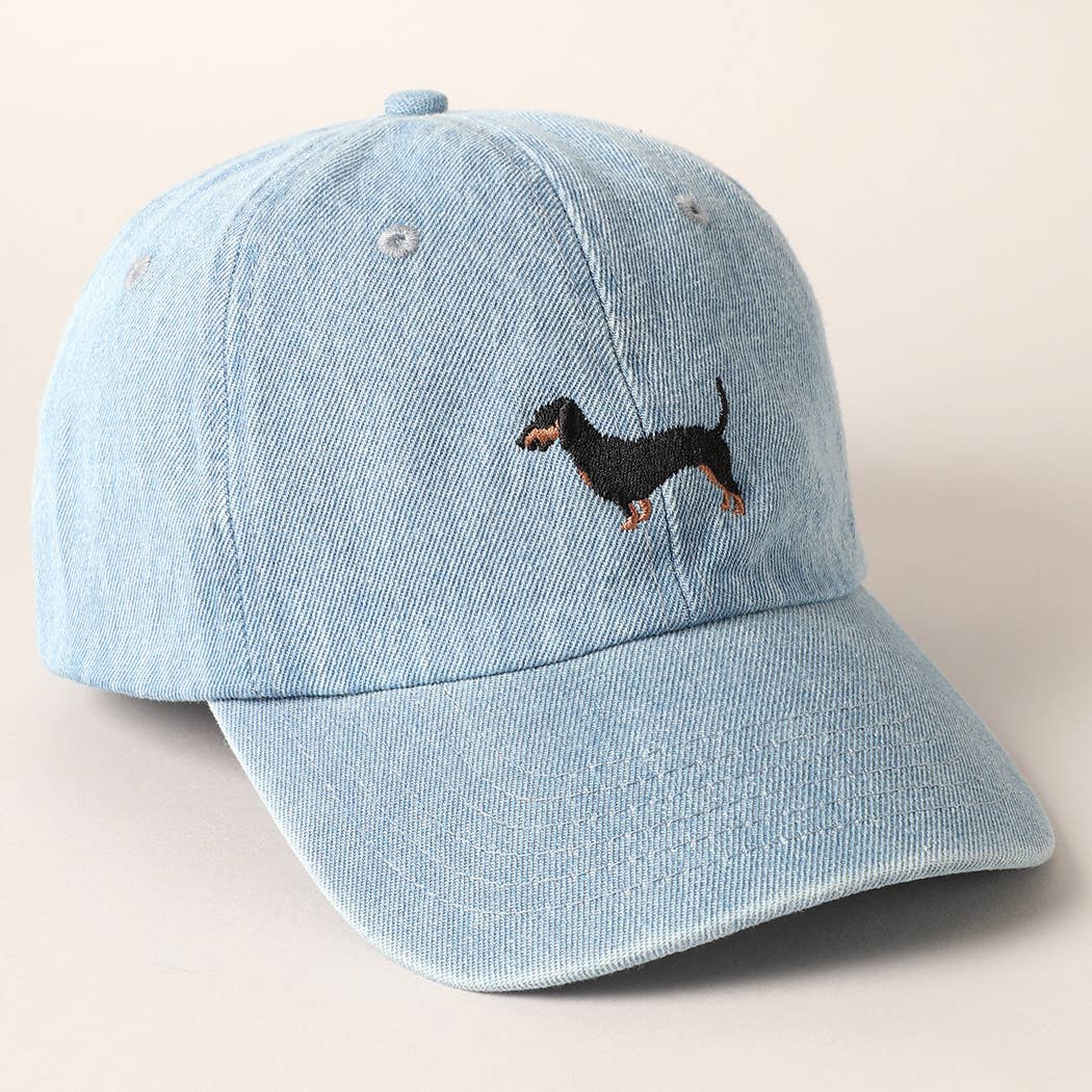 Light blue denim cap with embroidered dachshund on a beige background
