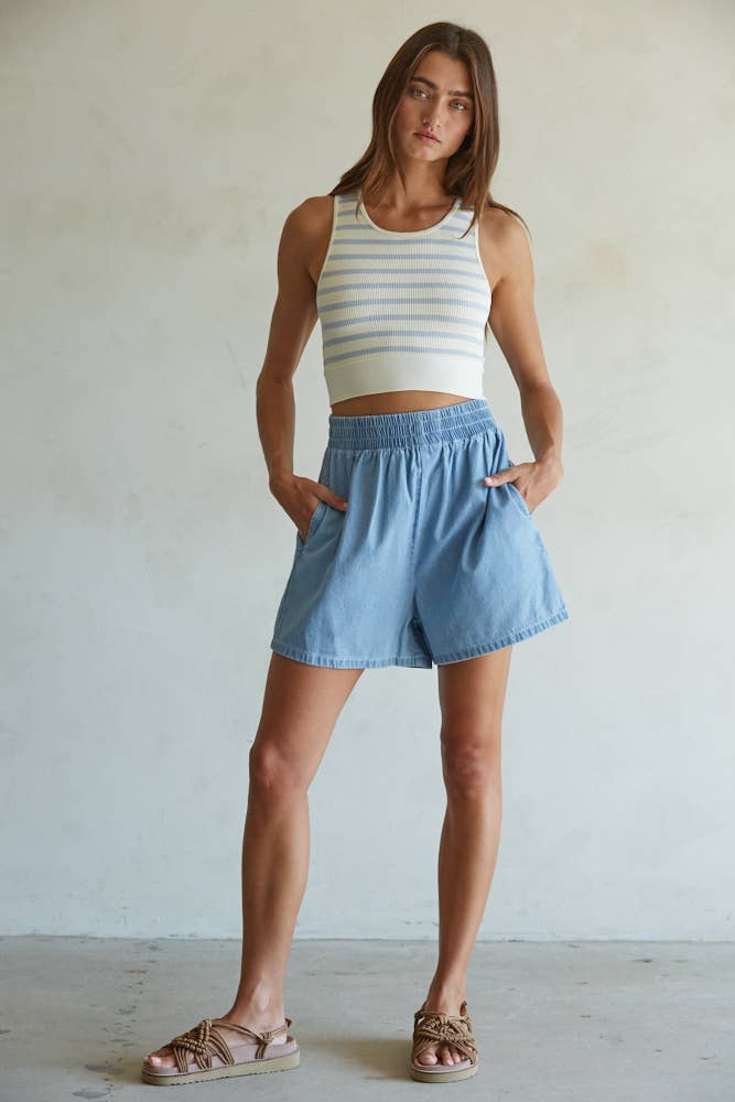Model wearing a ribbed cropped racerback tank with navy and cream horizontal stripes, styled with an olive mini skirt.