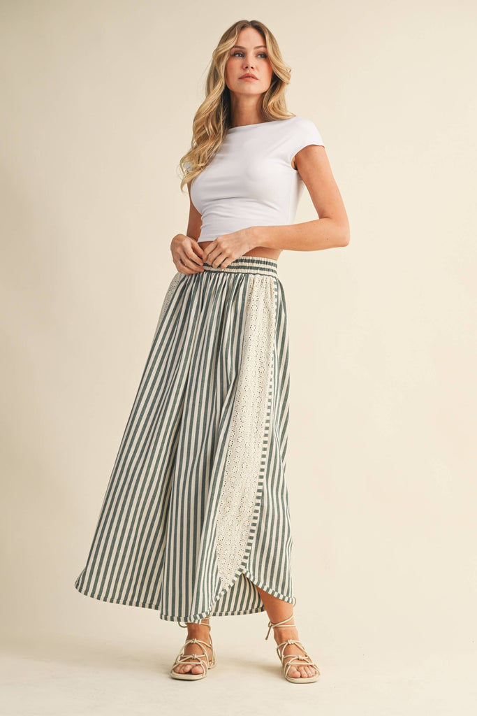 Woman wearing a white top and striped skirt on a beige background