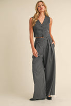 Woman wearing a sleeveless pinstriped vest and matching high-waisted wide-leg trousers.
