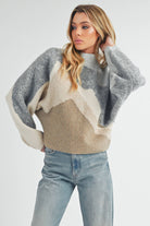 Front and back view of a woman wearing a color-block knit sweater in grey, cream, and taupe with a relaxed fit.