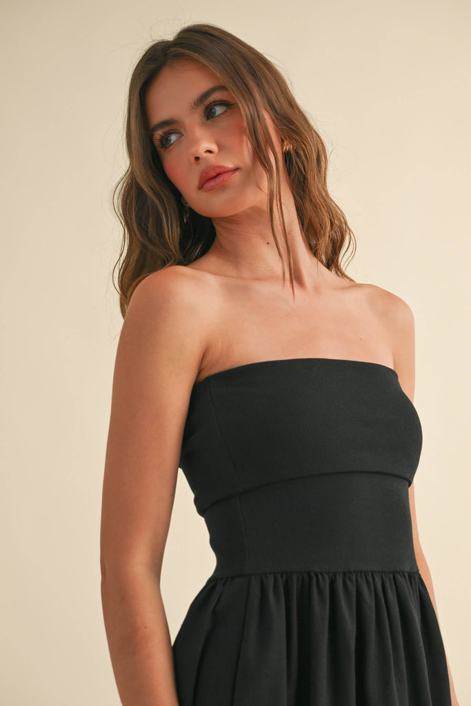 Woman wearing a black strapless maxi dress with a fitted bandeau bodice and flowy skirt.